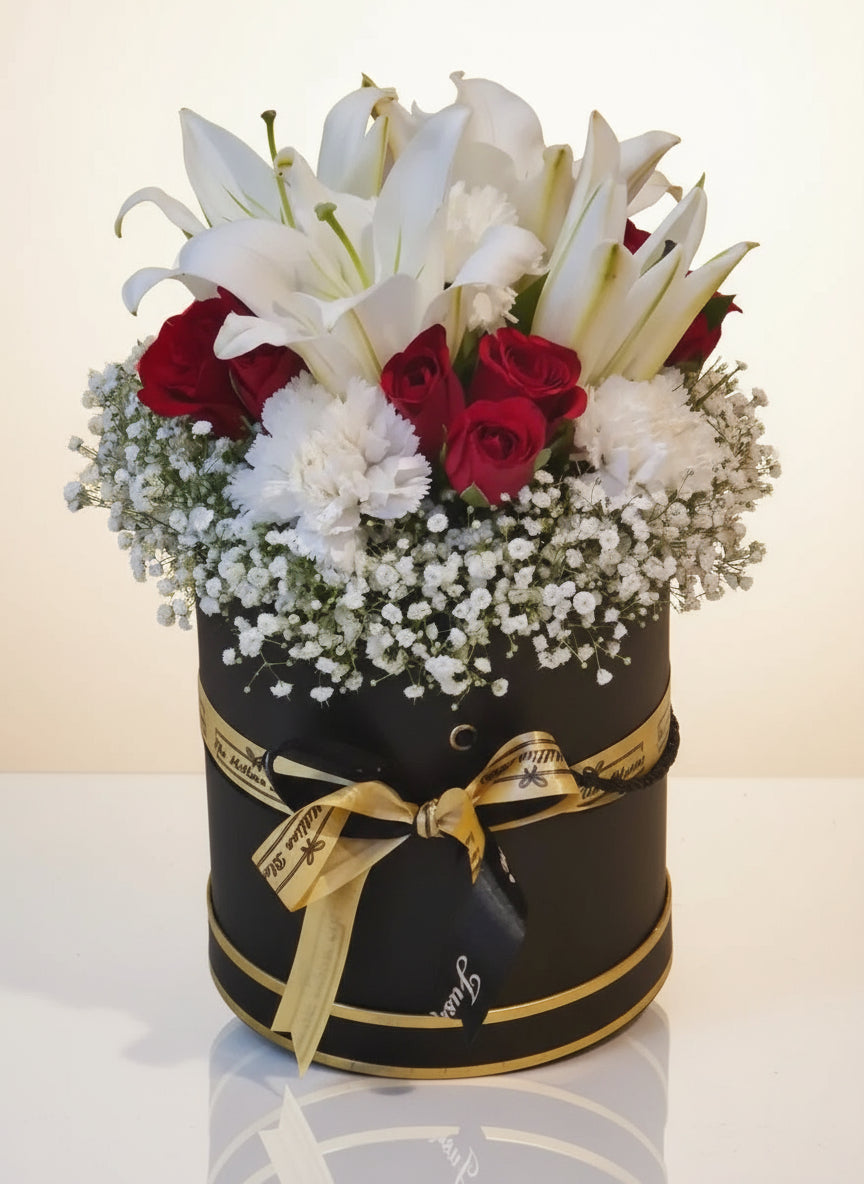 A luxurious arrangement of red roses, white lilies, and white carnations inside a black box. Perfect for any special occasion, this elegant floral design adds a touch of sophistication.