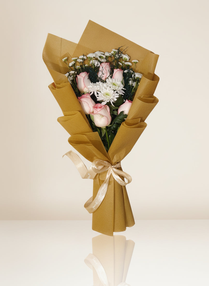 A stunning bouquet of red roses wrapped in vibrant yellow paper, adorned with a yellow ribbon and lush green leaves for an elegant touch.