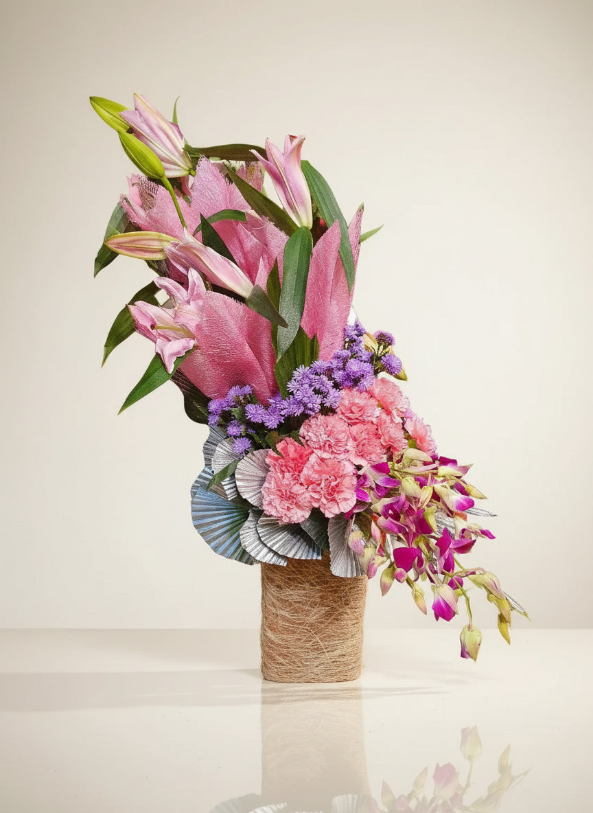 Discover the beauty of a delicate arrangement featuring pink lilies, carnations, and orchids, each showcasing its unique charm and elegance.